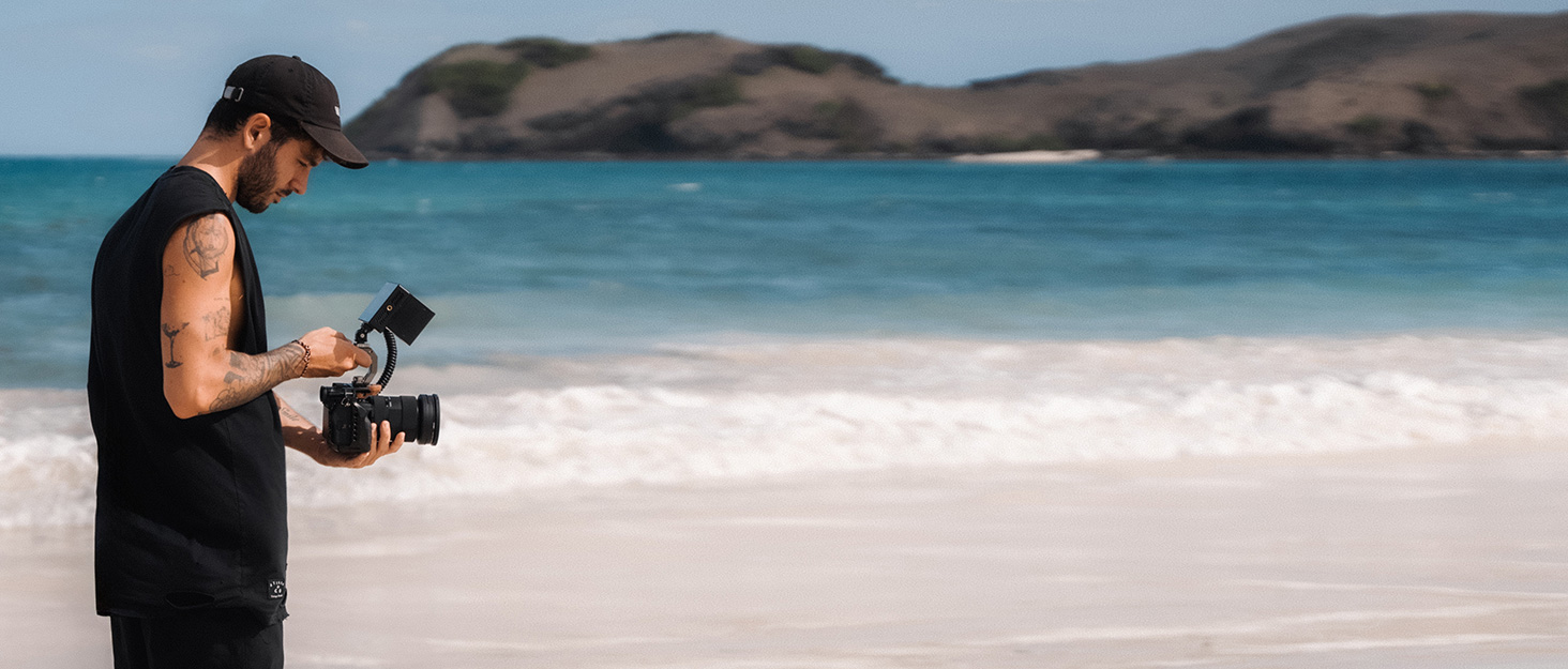 The videographer uses a monitor to capture beautiful beach scenery