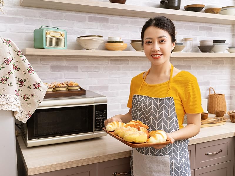 A woman holding a tray of food in front of the microwave oven