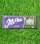 El texto dice «Milka». Envoltorio de barra de chocolate morado colocado sobre un fondo de hierba verde brillante.