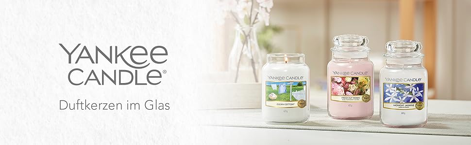 Der Text lautet „YANKEE CANDLE“. Auf weißen Verkaufsregalen sind mehrere Yankee Candle-Produkte ausgestellt, auf denen verschiedene Kerzengläser und Düfte sichtbar sind.