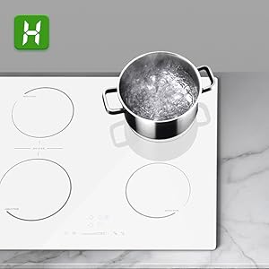 Stainless steel pot with water on white induction cooktop surface, with circular cooking zone markers visible.