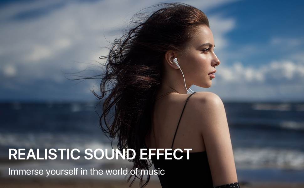 Woman with long dark hair facing the ocean, wearing earphones. Text overlay: 'REALISTIC SOUND EFFECT - Immerse yourself in the world of music'.