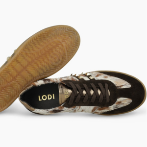 Zapatilla deportiva con detalles de gamuza y piel negras, con la marca LOGI, sobre un fondo blanco con suela de goma gomosa.