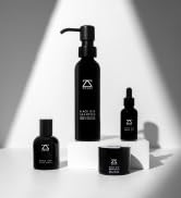 Collection of black cosmetic bottles and containers in various sizes, displayed against white background, showing product packaging range.