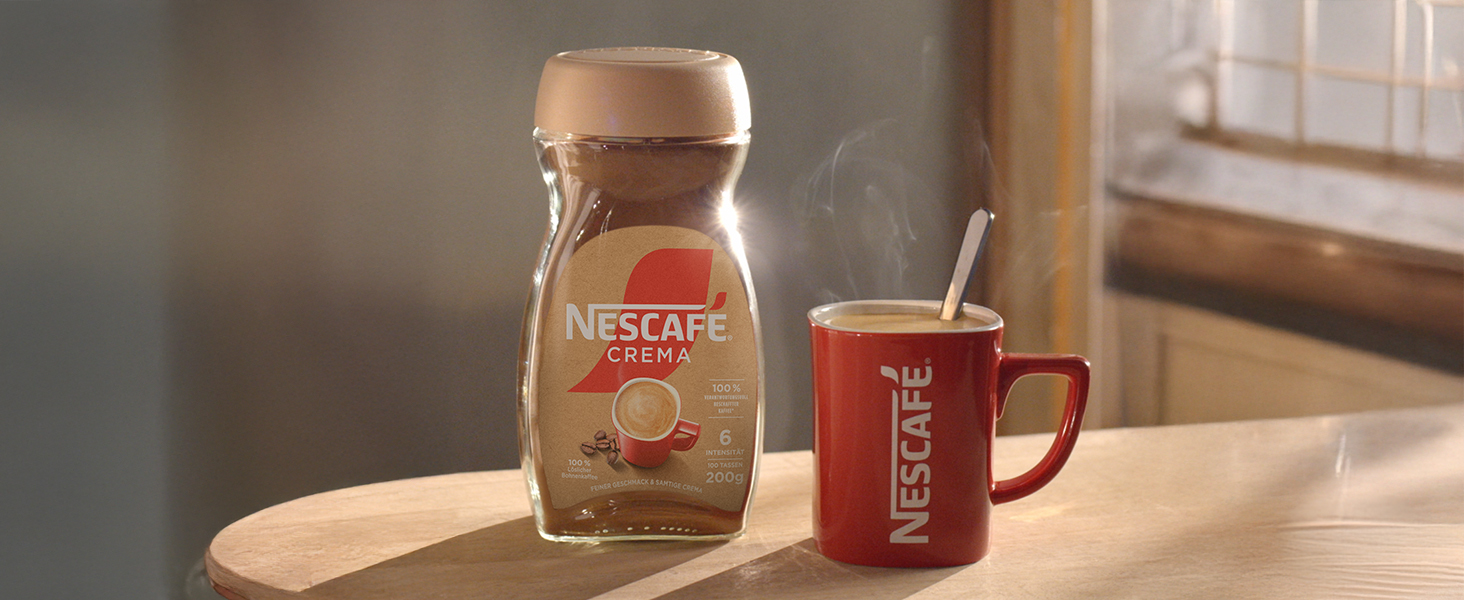 Glasgefäß und roter Keramikbecher auf einer Holzoberfläche bei warmem Licht angeordnet.