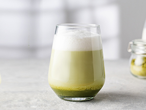 un vaso de leche con una bebida verde espumosa por encima