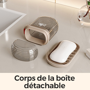 Porte-savon de forme ovale avec couvercle en plastique gris côtelé. Le couvercle est amovible, révélant une base en céramique blanche. Produit présenté démonté sur un plan de travail léger