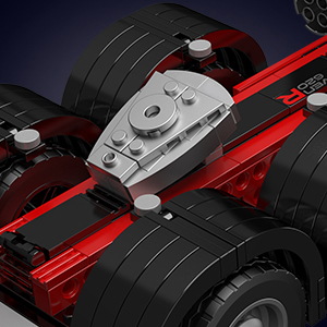 Close-up of a red and silver remote-controlled car chassis, showing wheels, suspension, and central control unit.
