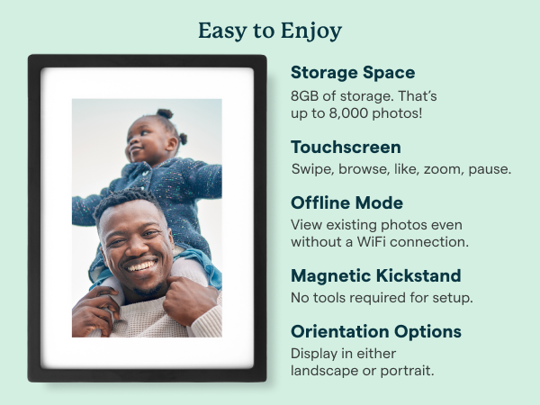 Skylight digital photo frame on table, with hand holding phone.