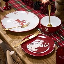 Holiday table setting with red and white plates featuring reindeer design on red plaid tablecloth. Gold utensils and small coordinating dish visible.