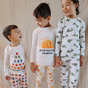 image of 3 siblings standing side by side, all wearing pjs from hungry caterpillar collection
