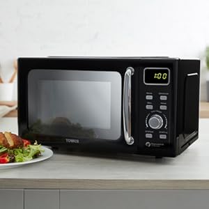 Black microwave oven on white counter, shown with food preparation sequence and digital display.