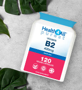 White bottle of vitamin B2 supplements. Label shows 120 veggie capsules, 400mg dosage. Bottle placed on white surface with green leaves in background.
