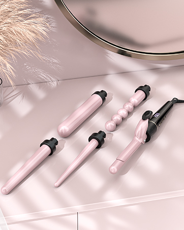 Ensemble d'outils de coiffure roses comprenant des baguettes à friser et un fer plat sur une surface rose pâle avec décoration en plumes