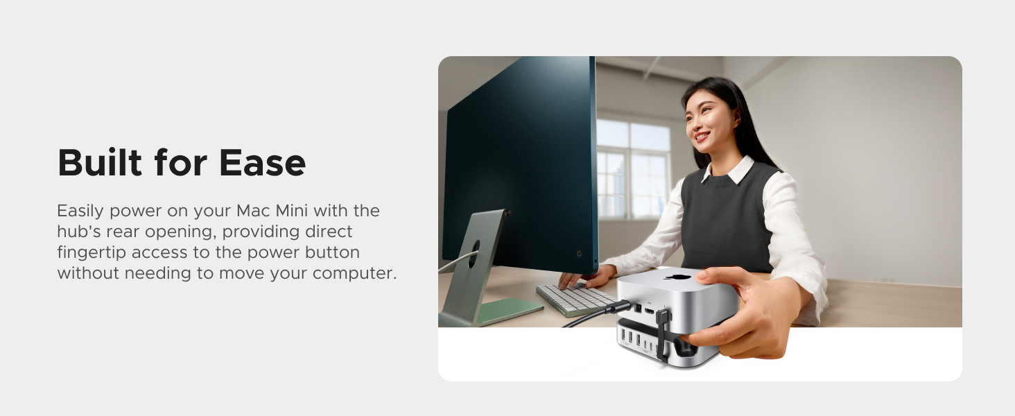 Desktop computer setup with green-tinted monitor. Woman holding coffee mug near compact docking station with multiple ports, designed for easy connection to Mac Mini.