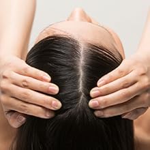 una donna con le mani sulla testa e i capelli trattenuti dalla testa.