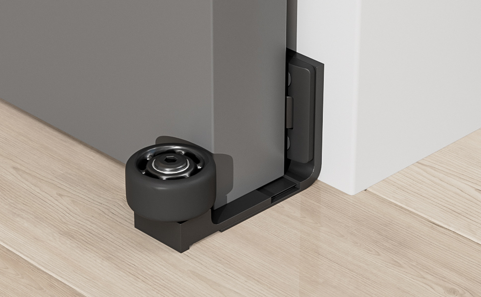Black L-shaped door stopper with a circular roller, installed at the base of a white door on light wooden flooring.