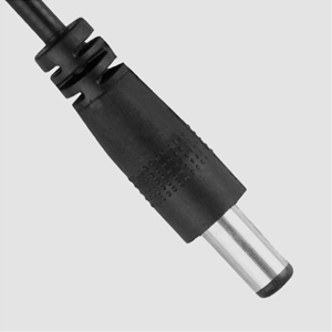 Close-up of a black cylindrical electronic connector or plug with a silver metal tip. The body has ribbed texture and a stepped design near the cable end.