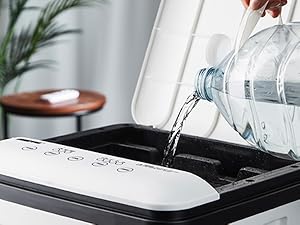 Water is poured from bottle into white electronic device with water tank showing water filtration or humidifier filling process.