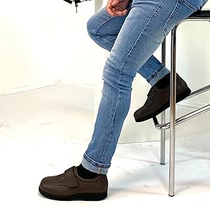 Mann sitzt auf Hocker und trägt das braune Modell des Natural Feet Klaas XL.