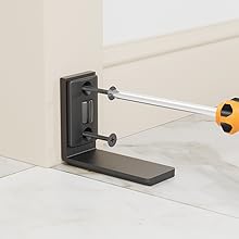 Schwarze L-förmige Wandhalterung mit verstellbaren Schrauben, die mit einem Schraubendreher mit gelbem Griff an der weißen Wand befestigt werden