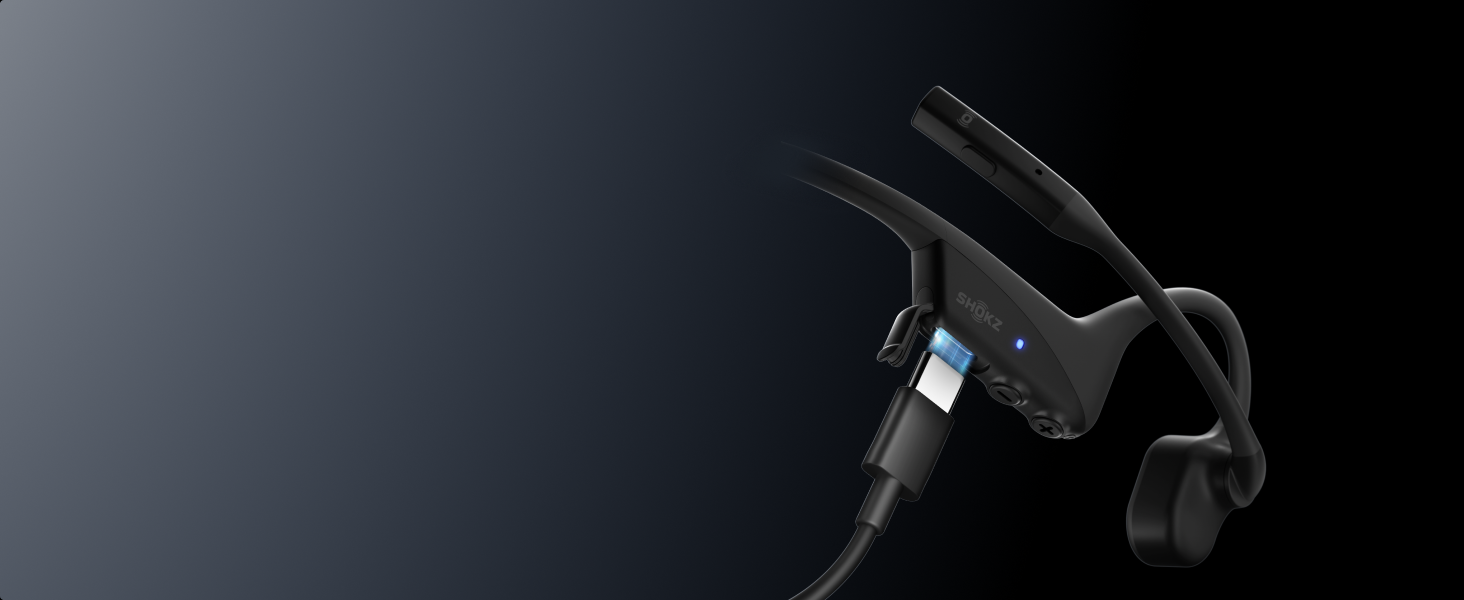 Nahaufnahme eines schwarzen elektronischen Geräts oder Headsets vor dunklem Hintergrund, mit sichtbarer kleiner blauer Anzeigelampe