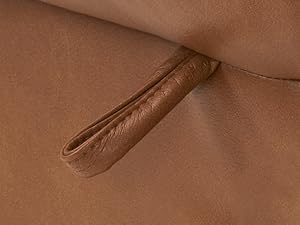 Nahaufnahme einer braunen Ledergürtelschlaufe, die an einem weichen, hellbraunen Stoff- oder Ledermaterial befestigt