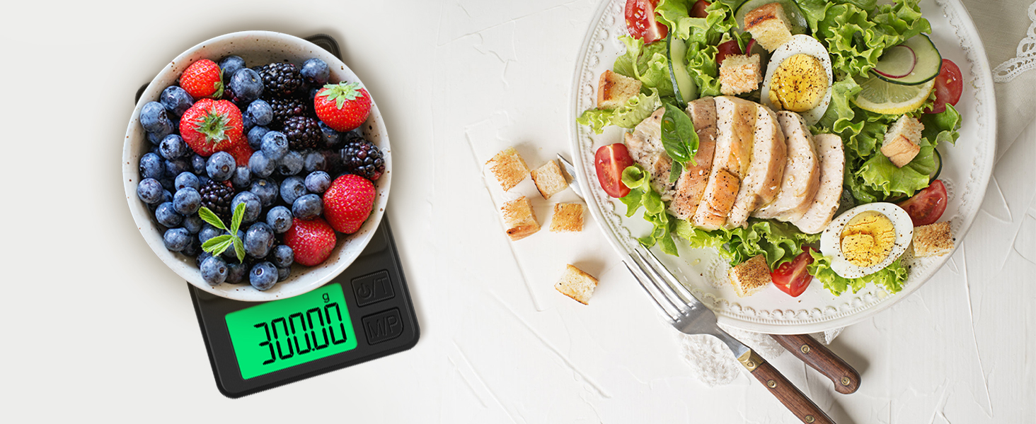 Digital kitchen scale displaying 300.0g, weighing a bowl of mixed berries. Adjacent is a plate with a healthy salad and sliced chicken.