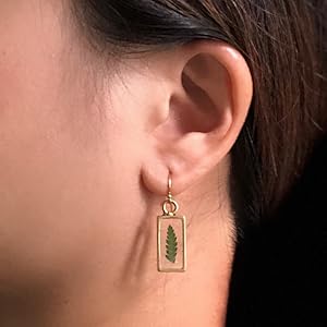 A person wearing a Olive Bella fern earrings on the ear