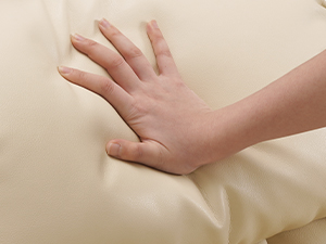 Nahaufnahme eines Drucks, der auf einen beigen Memoryschaum oder eine gepolsterte Oberfläche ausgeübt wird, was eine Materialdrückung zeigt.