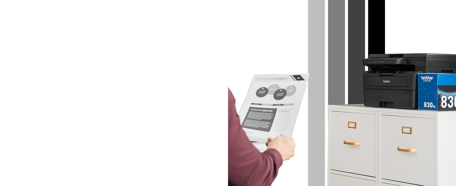 Person in small office reviewing b/w document printed from Brother HL-L2480DW 3-in-1 laser printer