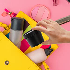 a woman's hand holding a cosmetic bag with a variety of makeup products in it.