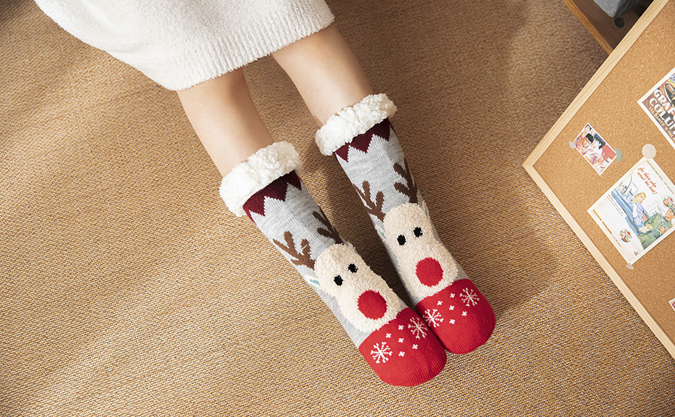 Cozy winter socks with reindeer pattern and red toe caps displayed on beige surface near corner of photo frame.