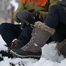man and woman sitting in the snow the woman is wearing dark gray snow boots