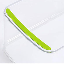 Close-up of a white cutting board corner with a bright green non-slip edge. The board has a sleek, modern design with rounded corners.