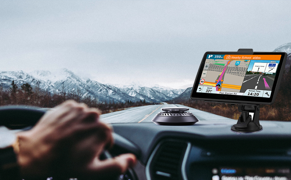 GPS navigation device mounted on car dashboard, displaying colorful map and route information. Snowy mountains visible through windshield.