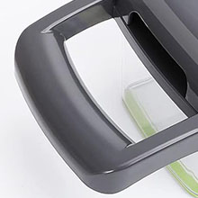 Close-up of a dark gray plastic or rubber device frame with a curved edge and rectangular opening, partially revealing a light-colored surface beneath.