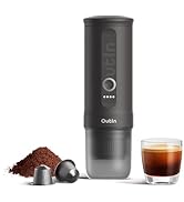 Portable black coffee maker with coffee grounds and an espresso shot in glass cup. Shows brewing components and ground coffee scattered nearby.