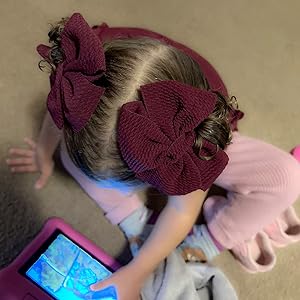 toddler girls play ipad in a pair of red hair bows