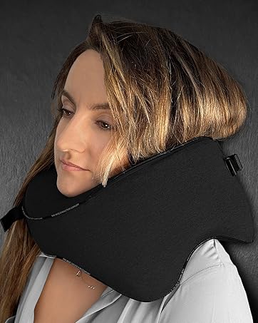 Black travel neck pillow supporting a person's head and neck. Designed for comfort during sleep or rest while traveling.