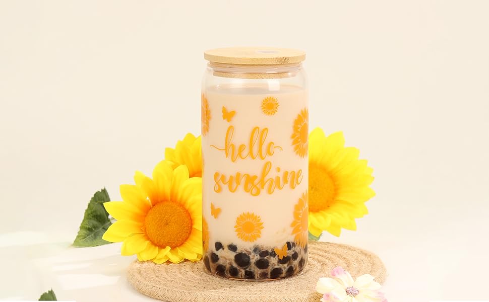 Glasgefäß mit Holzdeckel mit Milchtee und Boba-Perlen, verziert mit dem Text „Hello Sunshine“ und Sonnenmotiven, dekoriert mit Sonnenblumen