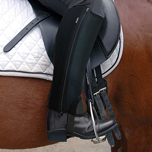 Image of a riders leg in the saddle wearing the half chap