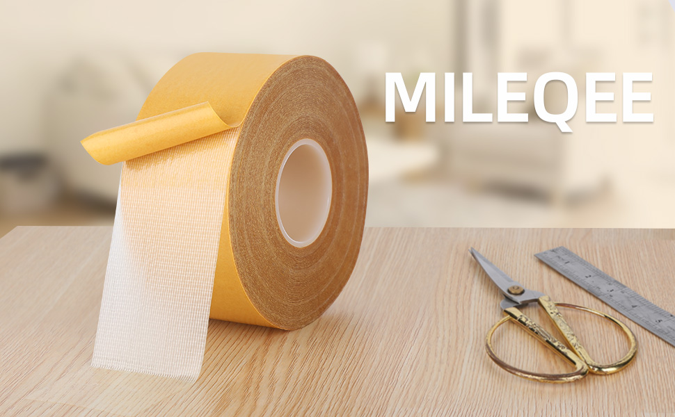 A double side tape pulled out a bit and sticking on a desk, a ruler and a scissors by it's side