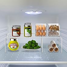 Clear plastic refrigerator organizer bins showing compartmentalized storage for various food items, mounted on fridge wall.