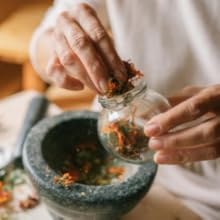 Sequence of hands using a traditional stone mortar and pestle to grind ingredients, shown from different angles.