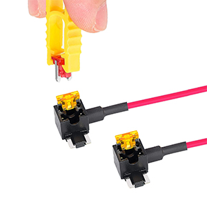 Two black electronic components with yellow tops and long pink wires. Possibly switches or sensors. Partial view of a pink object above.