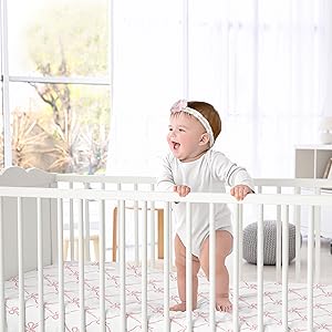 baby standing on crib sheet in crib