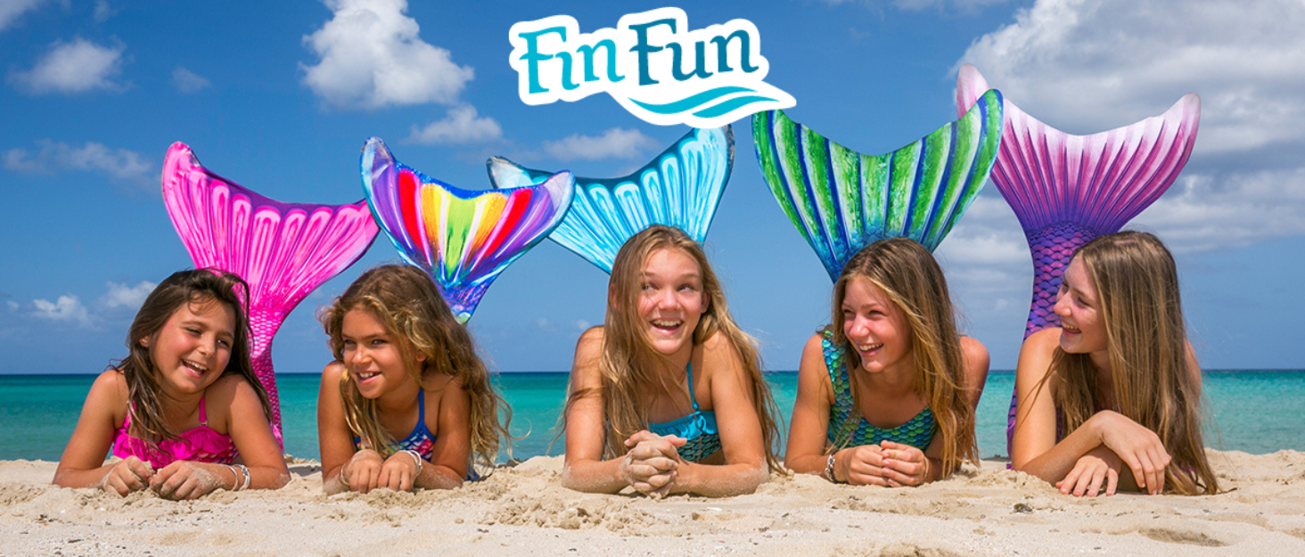 Girls on the beach in mermaid tails swimming