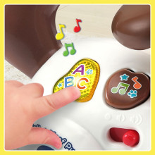 Kid pushes yellow ABC button on back of puppy. Notes illustrate music.