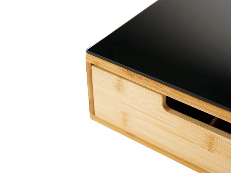 Organizer da scrivania in legno con superficie superiore nera e base in legno chiaro. Presenta un cassetto o uno scomparto con una maniglia ritagliata sulla parte anteriore